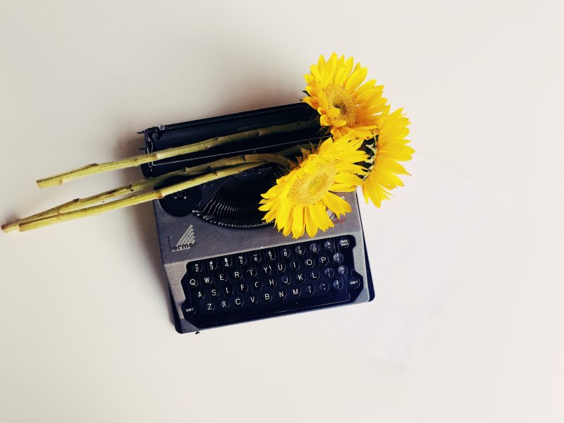 Yellow sunflowers on a vintage hermés typewriter, suggesting the age of the typewriter is over.