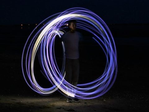 Time lapse photo of person making circles with a violet glow stick. Photo by Rafael Garcin on Unsplash.