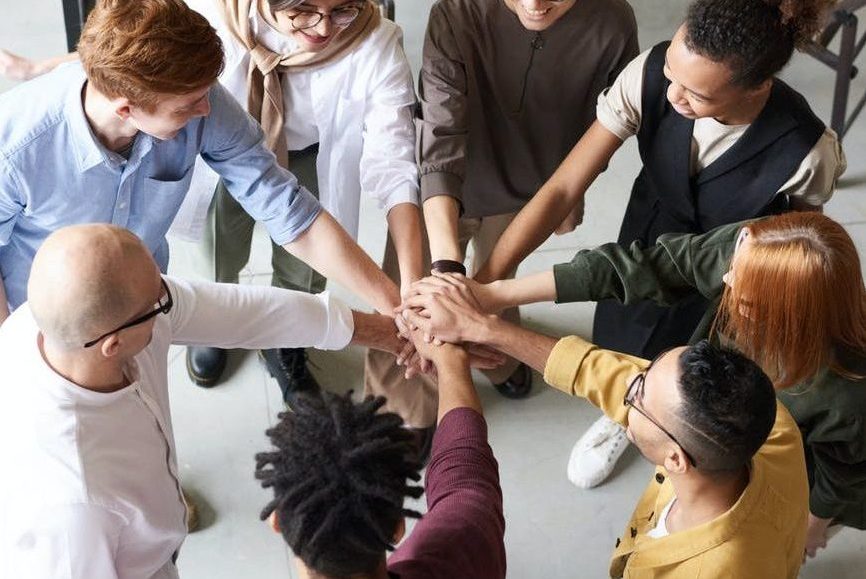 people putting hands together in a circle. Photo by fauxels on Unsplash.